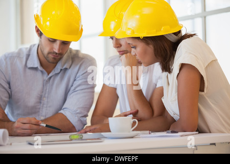 Architects in yellow helmets working on blueprints Stock Photo