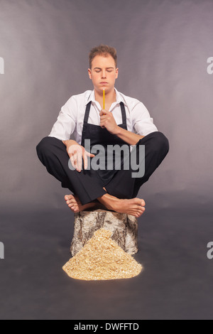 Thoughtful man in dungarees chipping wood Stock Photo