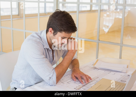 Businessman working on blueprints in office Stock Photo