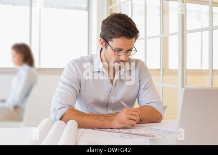 Businessman working on blueprints in office Stock Photo