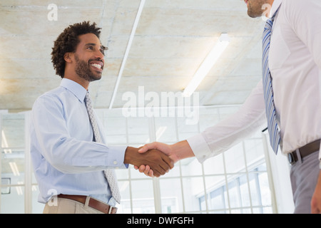 Two businessmen shaking hands in office Stock Photo