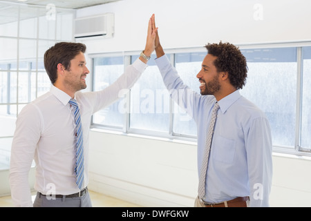 Smiling businessmen joining hands together in office Stock Photo
