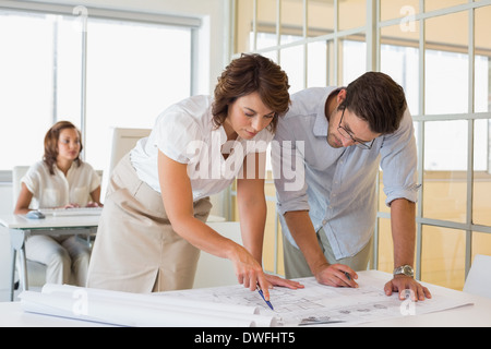 Concentrated colleagues working on blueprints at office Stock Photo