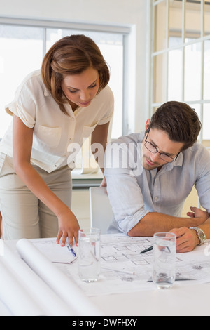 Concentrated colleagues working on blueprints at office Stock Photo