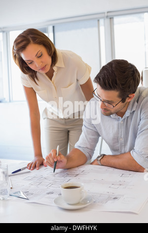 Concentrated colleagues working on blueprints at office Stock Photo
