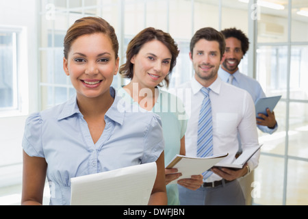 Business colleagues holding notepads in row at office Stock Photo