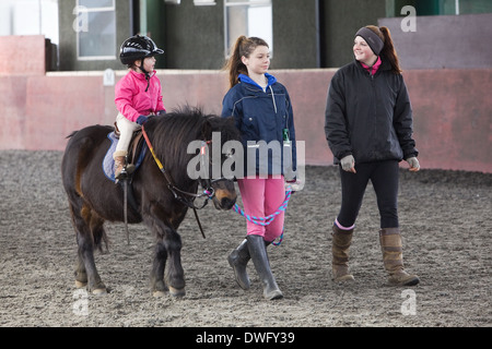 A four year old girl riding a pony during a riding lesson in North Lincolnshire, England, 2014 Stock Photo