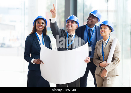 group of construction workers holding blue print and discussing project Stock Photo