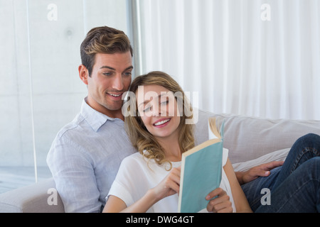 Young couple reading book on couch Stock Photo
