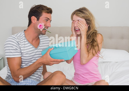 Man surprising woman with a gift box in bed Stock Photo