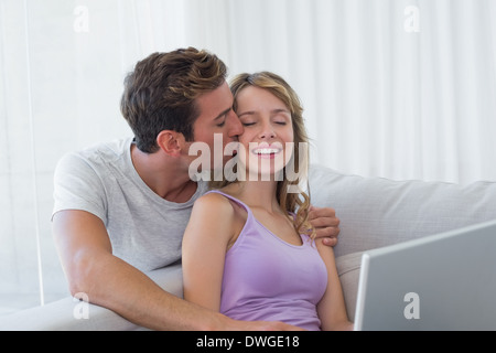 Loving young couple using laptop on couch Stock Photo