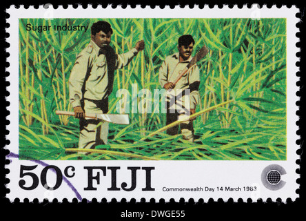 A 1983 Fiji postage stamp with an illustration of two mean harvesting sugar cane. Stock Photo