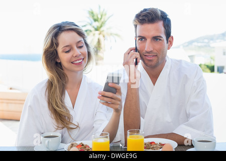 Couple using mobile phones while having breakfast Stock Photo