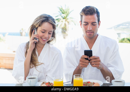Couple using mobile phones while having breakfast Stock Photo