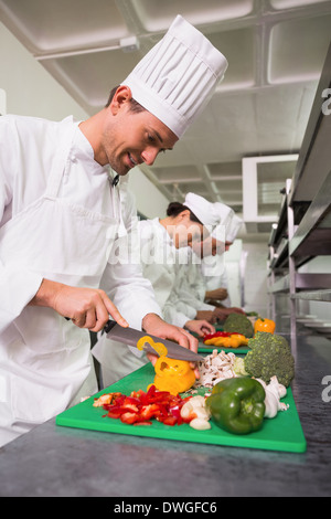 Row of trainee chefs slicing vegetables Stock Photo