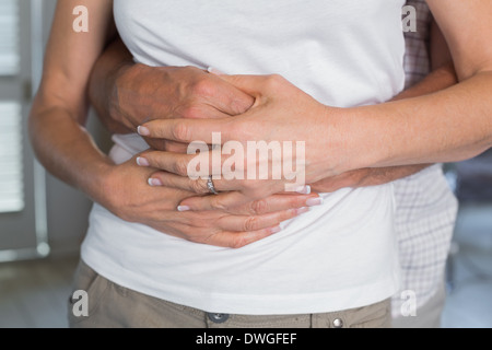 Mid section of a man embracing woman from behind Stock Photo