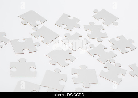 Blank jigsaw puzzle pieces on illuminated white background. Stock Photo