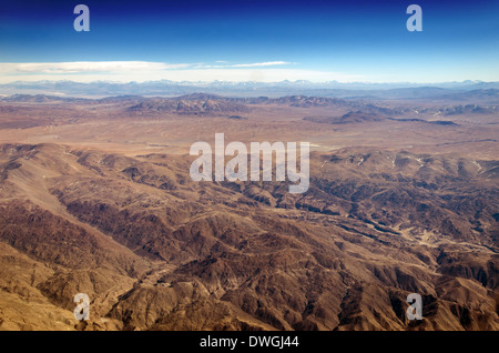 Dry desert and hills with snow capped mountains in the background somewhere over South America Stock Photo
