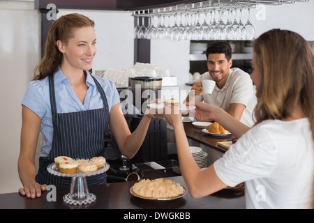 Cafe owner giving sweet food to a couple at coffee shop Stock Photo