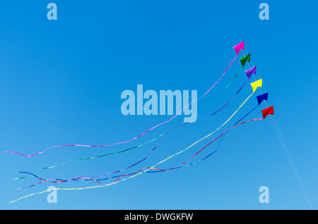 Rainbow colored kites flying against a beautiful blue sky Stock Photo