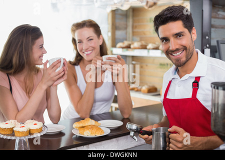 Women drinking coffee with male barista at coffee shop counter Stock Photo