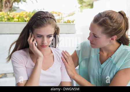 Woman consoling a friend while shes on call in caf├⌐ Stock Photo