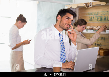 Businessman using laptop in office cafeteria Stock Photo