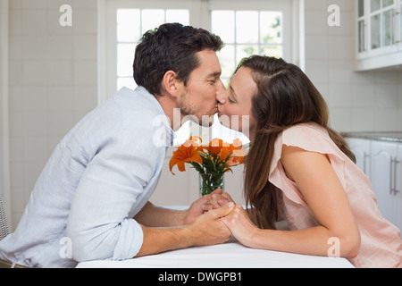 Side view of a loving couple kissing in kitchen Stock Photo