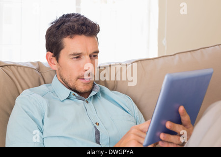 Relaxed man using digital tablet on couch Stock Photo