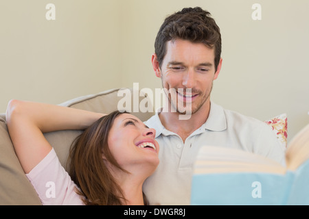 Loving couple reading book on couch Stock Photo