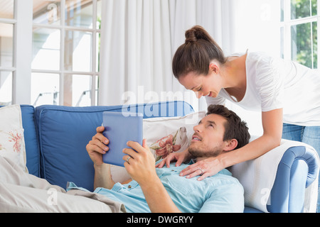 Loving couple with digital tablet in living room Stock Photo
