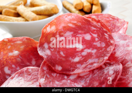 closeup of a plate with slices of salchichon, spanish cured sausage, and some picos, breadsticks in the background Stock Photo