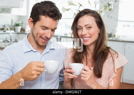 Happy young couple with coffee cups in kitchen Stock Photo