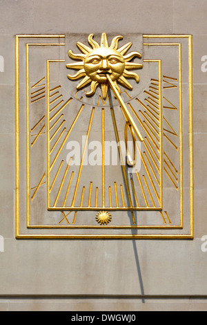 Sundial on wall of office building set into smooth stone wall Stock Photo