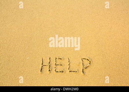 Help, written in sand on beach texture. Stock Photo