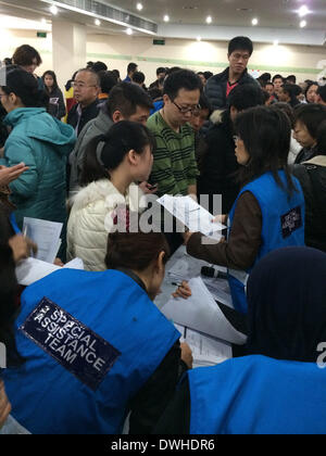 (140309) -- BEIJING, March 9, 2014 (Xinhua) -- Members of a special assistance team of Malaysian Airlines offer information forms to the relatives of those on board the missing flight, in Beijing, capital of China, March 9, 2014. The company will update relatives on the latest situation in every 15 minutes, said the airline's spokesman. The Malaysia Airlines Flight MH370, a Boeing B777-200, lost communication and radar signal on its flight from Malaysia's capital Kuala Lumpur to Beijing on early Saturday morning. On board were 227 passengers from 14 countries, including 154 Chinese, and 12 Mal Stock Photo