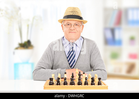 Elderly gentleman posing behind a chessboard indoors Stock Photo