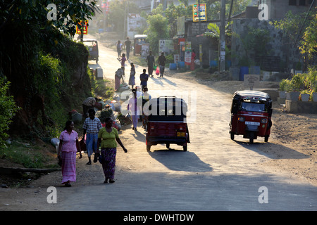 Pedestrians and tuk tuk motor taxis in street, early morning in Ella, Sri Lanka Stock Photo
