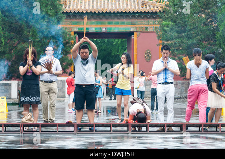 Buddhists burn incense and pray at Yonghegong Lama Temple in Beijing, China. Stock Photo