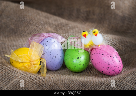 Colorful Easter eggs and decorative chickens on burlap background Stock Photo
