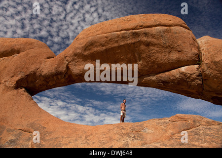 tourist at the rock arch near the granite mountain Spitzkoppe, Namibia, Africa Stock Photo