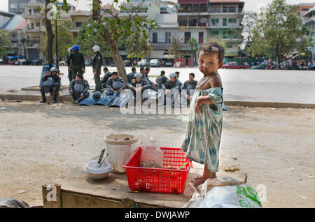 Phnom Penh, Cambodia. 5th Feb, 2014. A homeless child stands on her families dinner table as riot police await possible clashes. 8th March 2014, Phnom Penh, Cambodia. © George Nickels/NurPhoto/ZUMAPRESS.com/Alamy Live News Stock Photo
