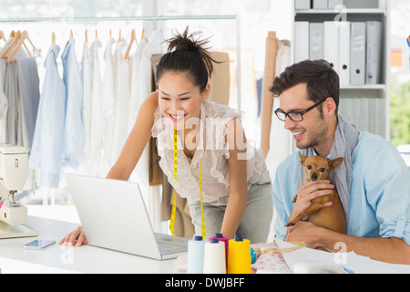 Fashion designers using laptop in studio Stock Photo