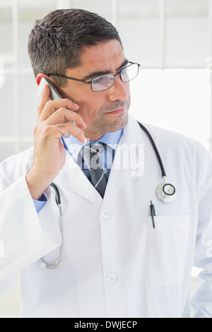 Serious male doctor using mobile phone Stock Photo
