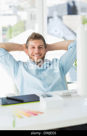 Handsome designer relaxing at his desk smiling at camera Stock Photo