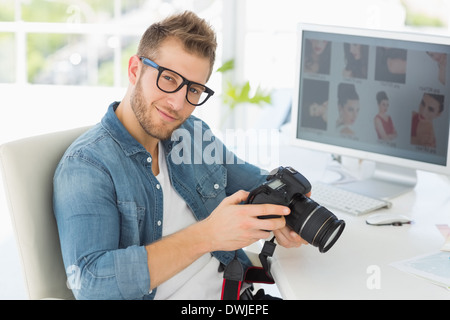 Handsome photographer holding his camera smiling at camera Stock Photo