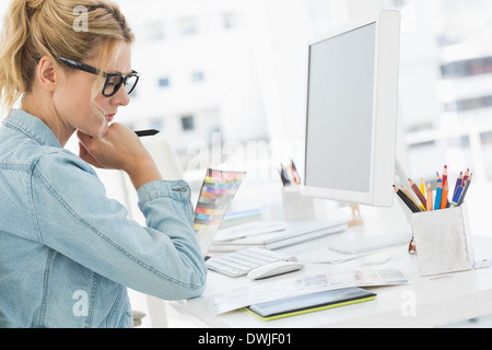 Blonde focused designer working at her desk Stock Photo