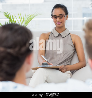 Therapist talking with couple on the couch and taking notes Stock Photo