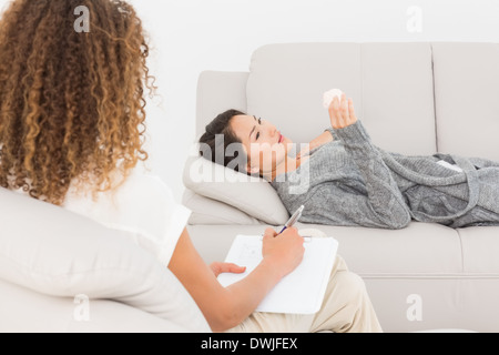 Therapist writing notes on her upset patient on the couch Stock Photo