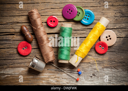 Set of colored sewing buttons and bobbin threads on wooden background Stock Photo